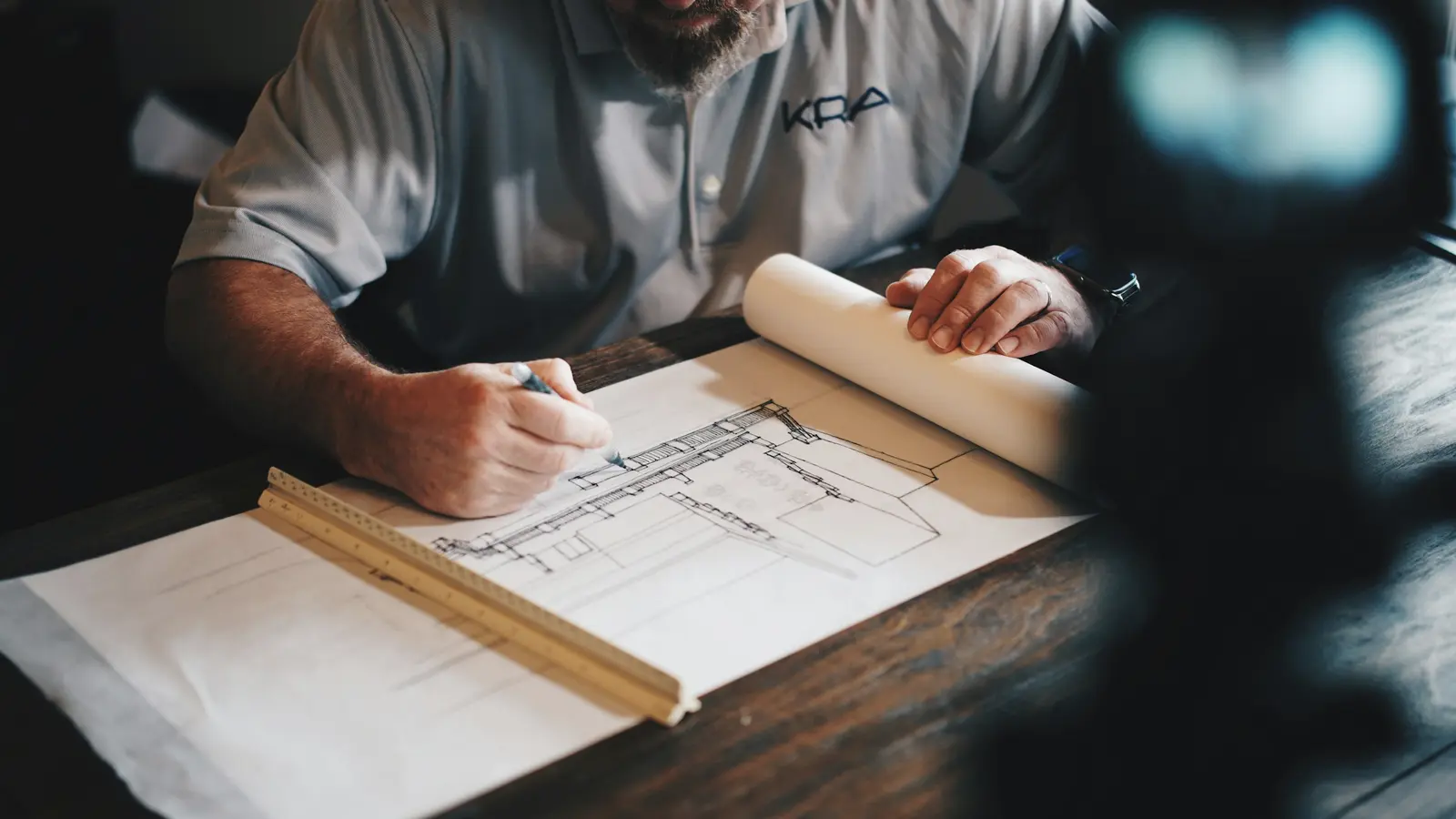 An architect drafting a plan at a wooden desk