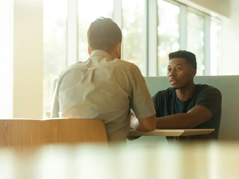 A broker talking a business owner through funding options in a sunlit office